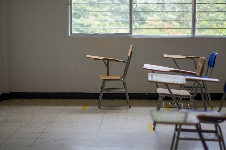 Quiet empty classroom interior with school desks by a large window
