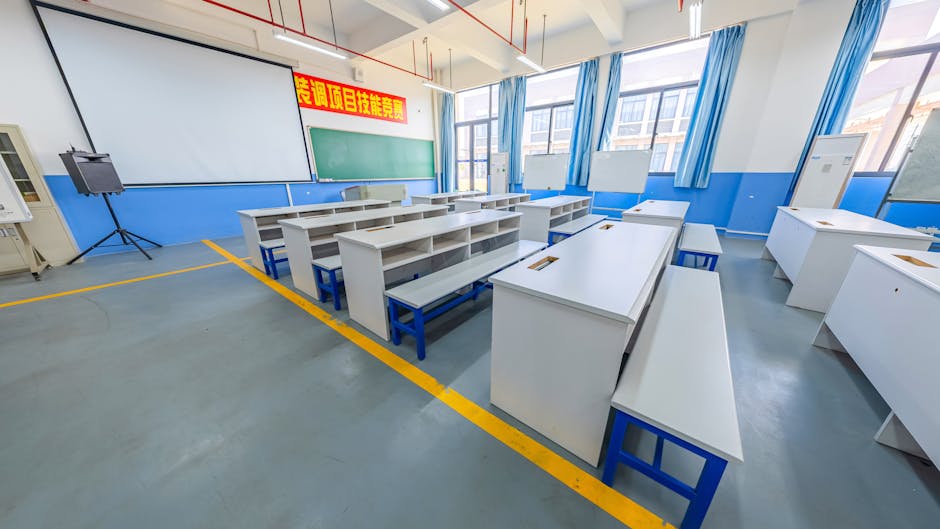A spacious modern classroom with blue and white decor, featuring desks and a projector screen.