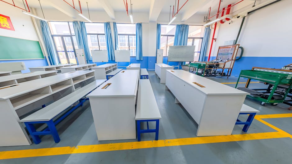 Spacious modern classroom with white desks, blue benches, and bright lighting.